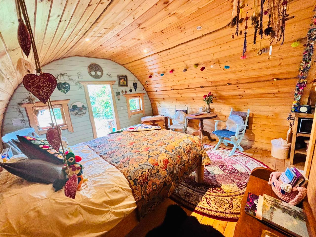 The double bed under the curved timber roof, with the open door onto the garden