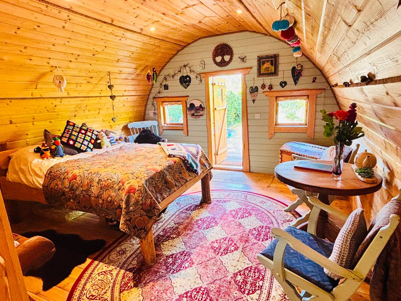 Wide view of the hobbit house interior — bed, patterned rug and tea table by the window
