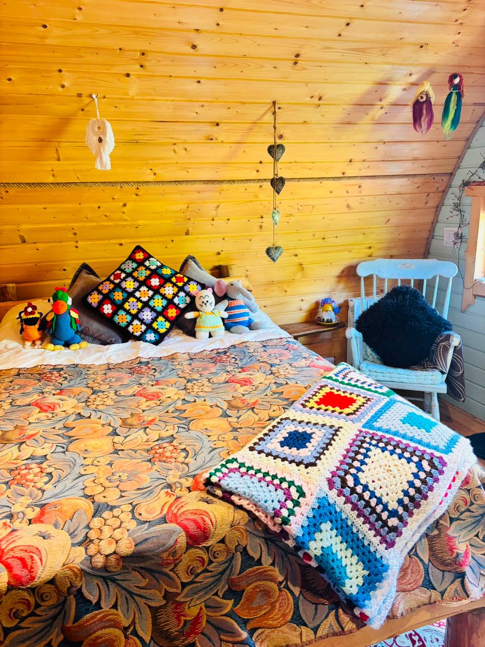 The double bed with crochet blankets, knitted toys and hanging hearts